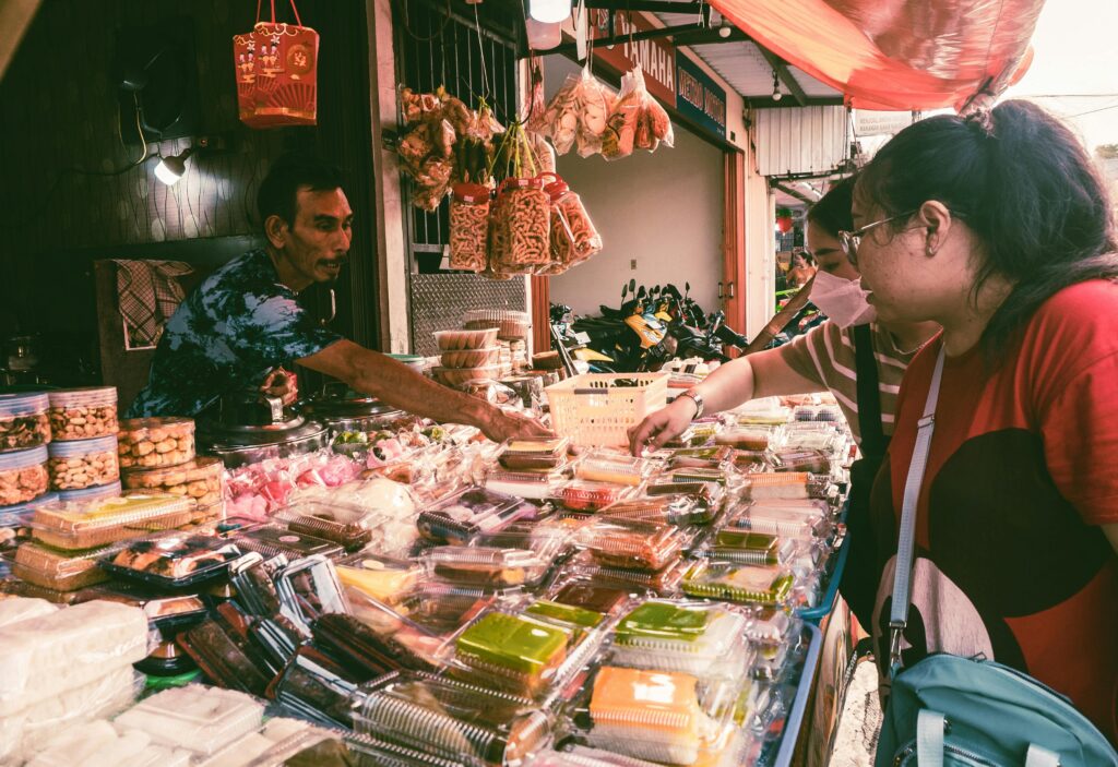 Market scene with customers buying various snacks from a vendor, vibrant setting.