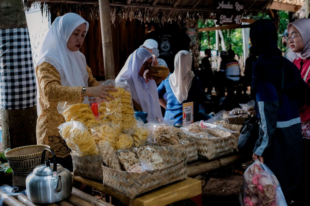 Street vendors selling traditional snacks at a busy West Java market, Indonesia.