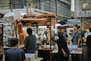Crowded street market scene with diverse individuals engaging in street food trade, highlighting urban life.
