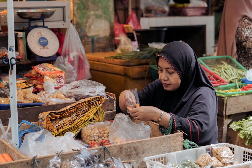 Indonesian market scene with a woman vendor organizing produce. Vibrant and authentic market atmosphere.