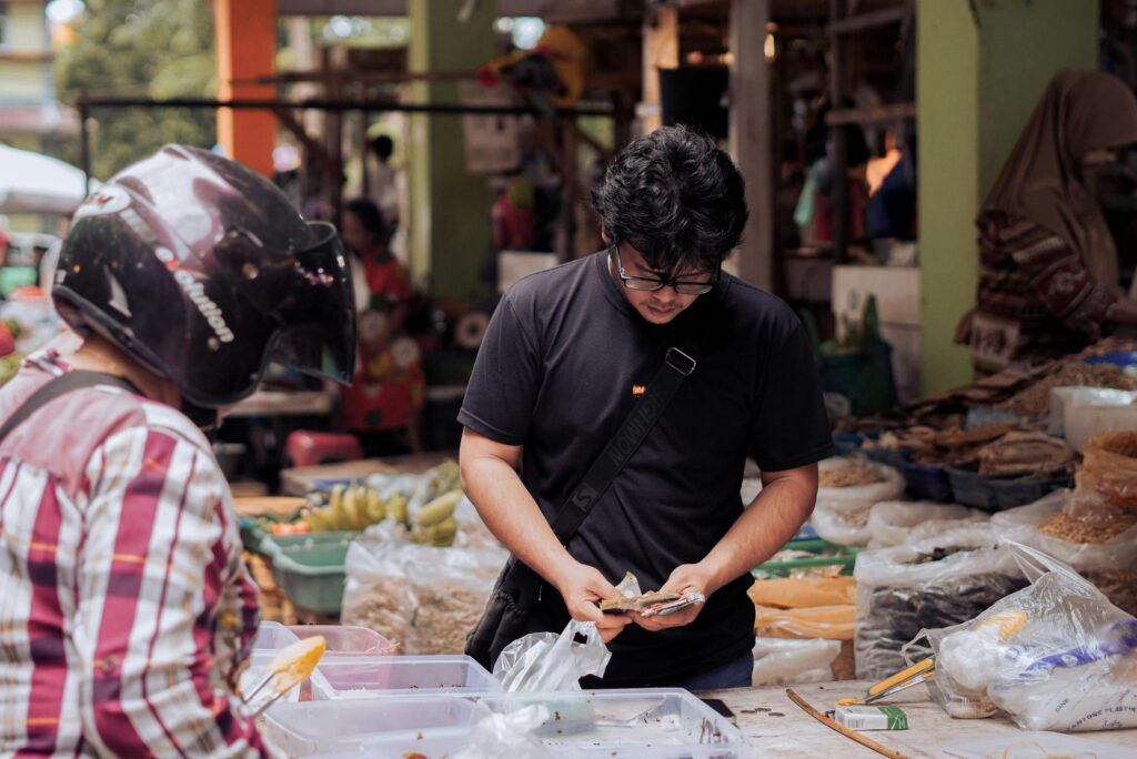 A man counting money at a bustling street market in Pontianak, Indonesia.